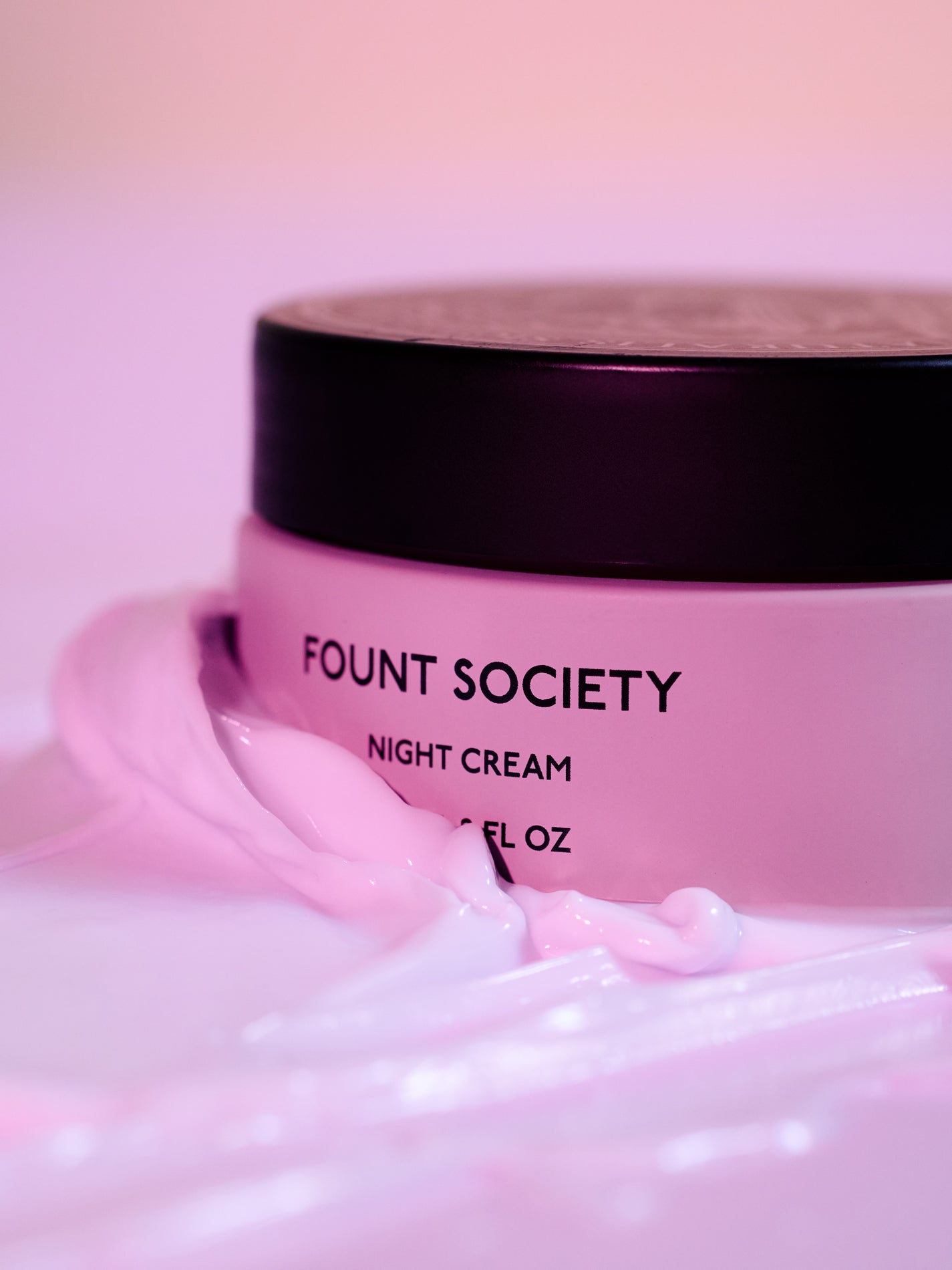 The Fount Society Night Cream is surrounded by rich, luxurious cream. It appears luminous and glowing in warm purple tones. |Size:Full Size