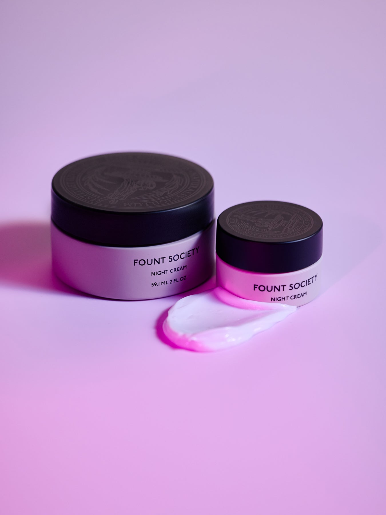 The Fount Society Night Cream in full size and mini size are pictured together with a dollop of the cream next to them. |Size:Mini