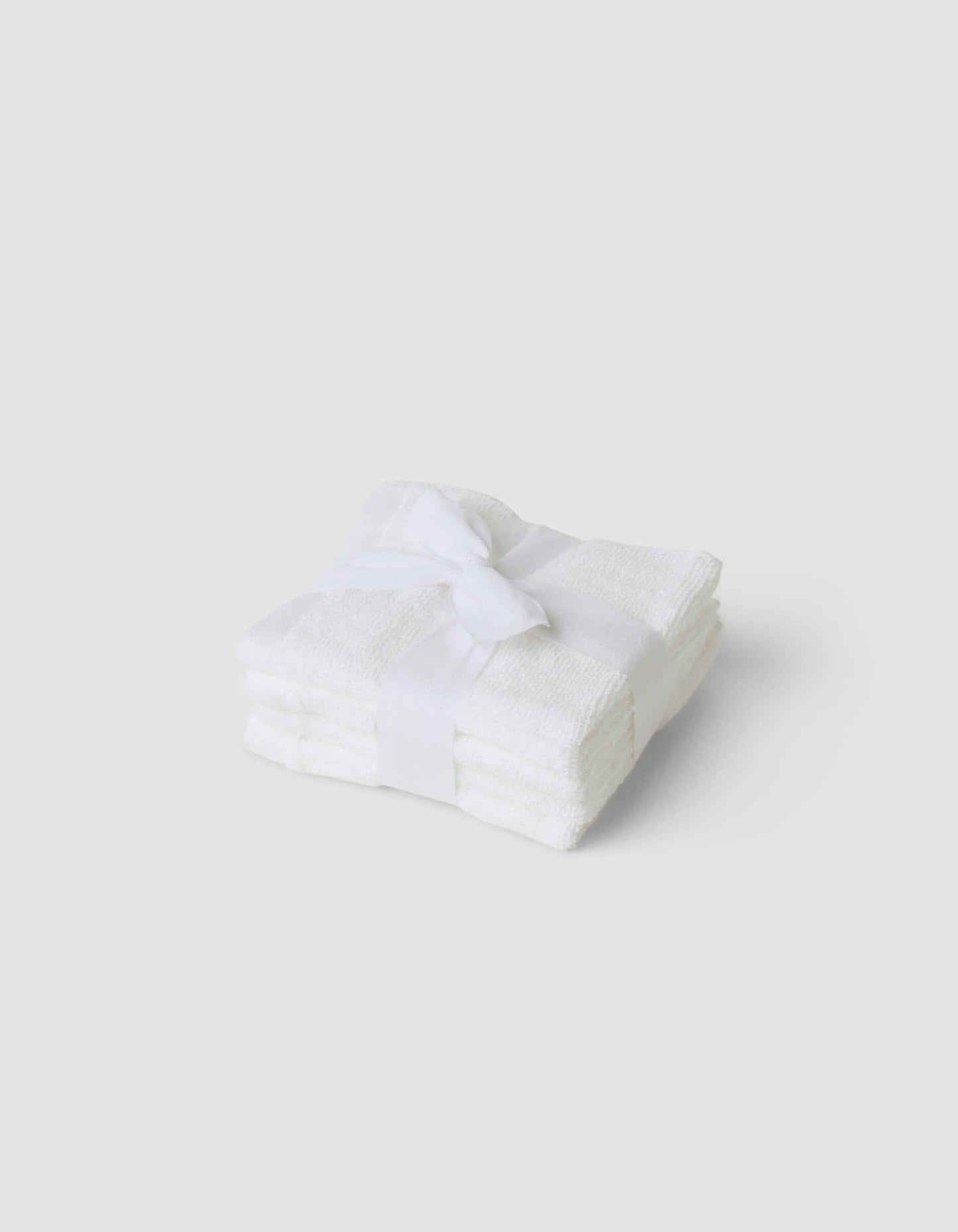 A stack of 4 white washcloths tied with a white ribbon|Color:White