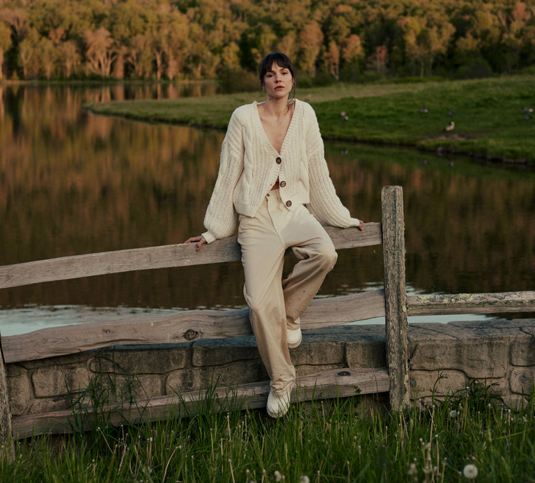 Woman sitting on a wooden fence in front of a lake