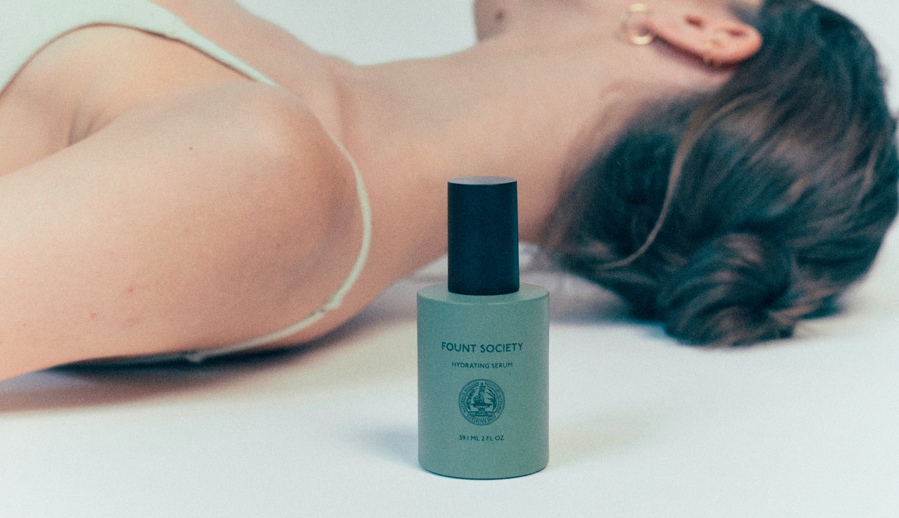 Fount Society's Hydrating Serum with a woman in background